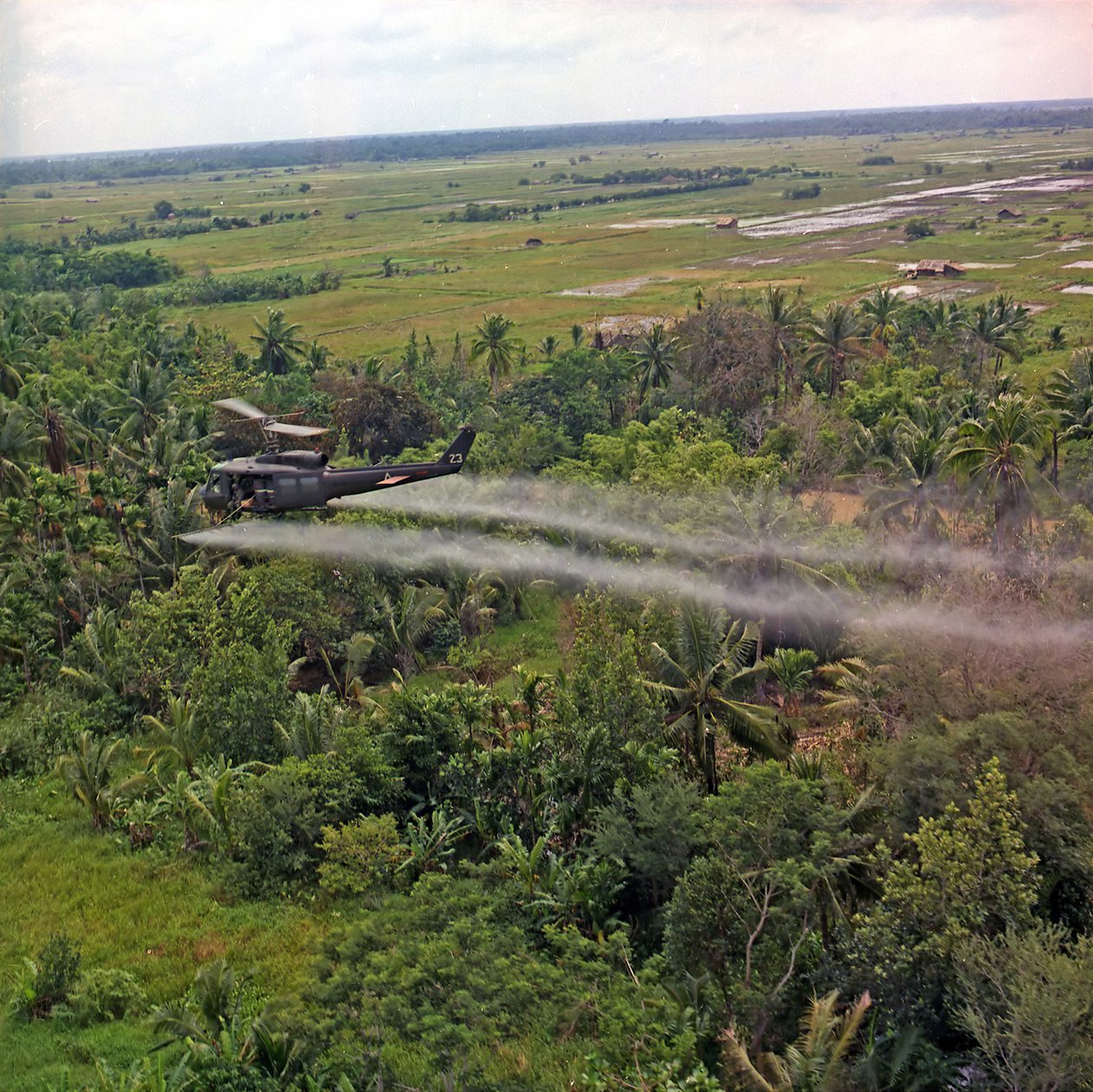 A UH-1D helicopter from the 336th Aviation Company sprays a defoliation agent on a dense jungle area in the Mekong Delta by American Photographer