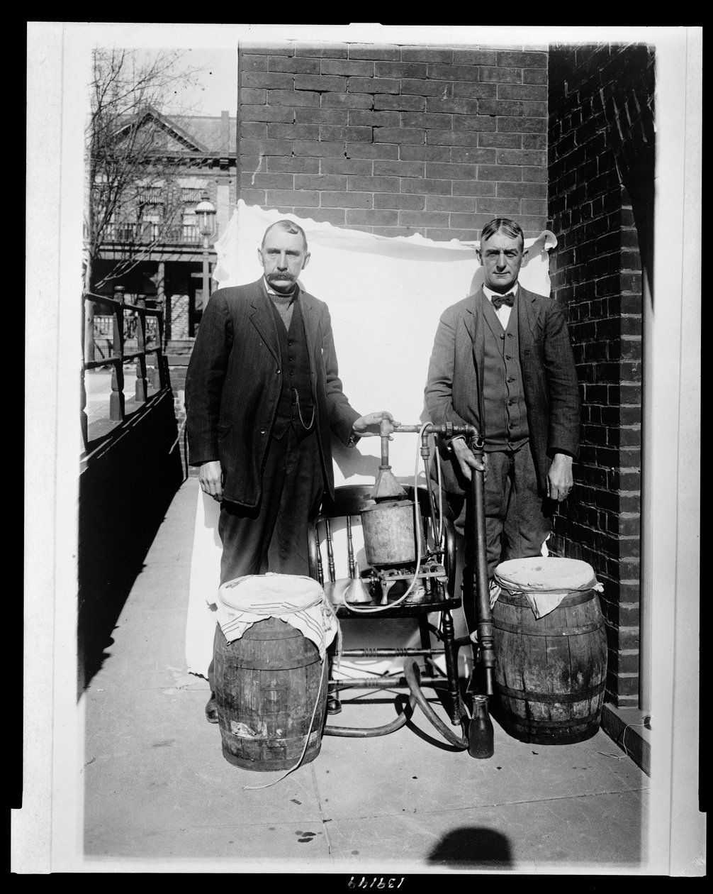 Two men posing with a whiskey still by American Photographer