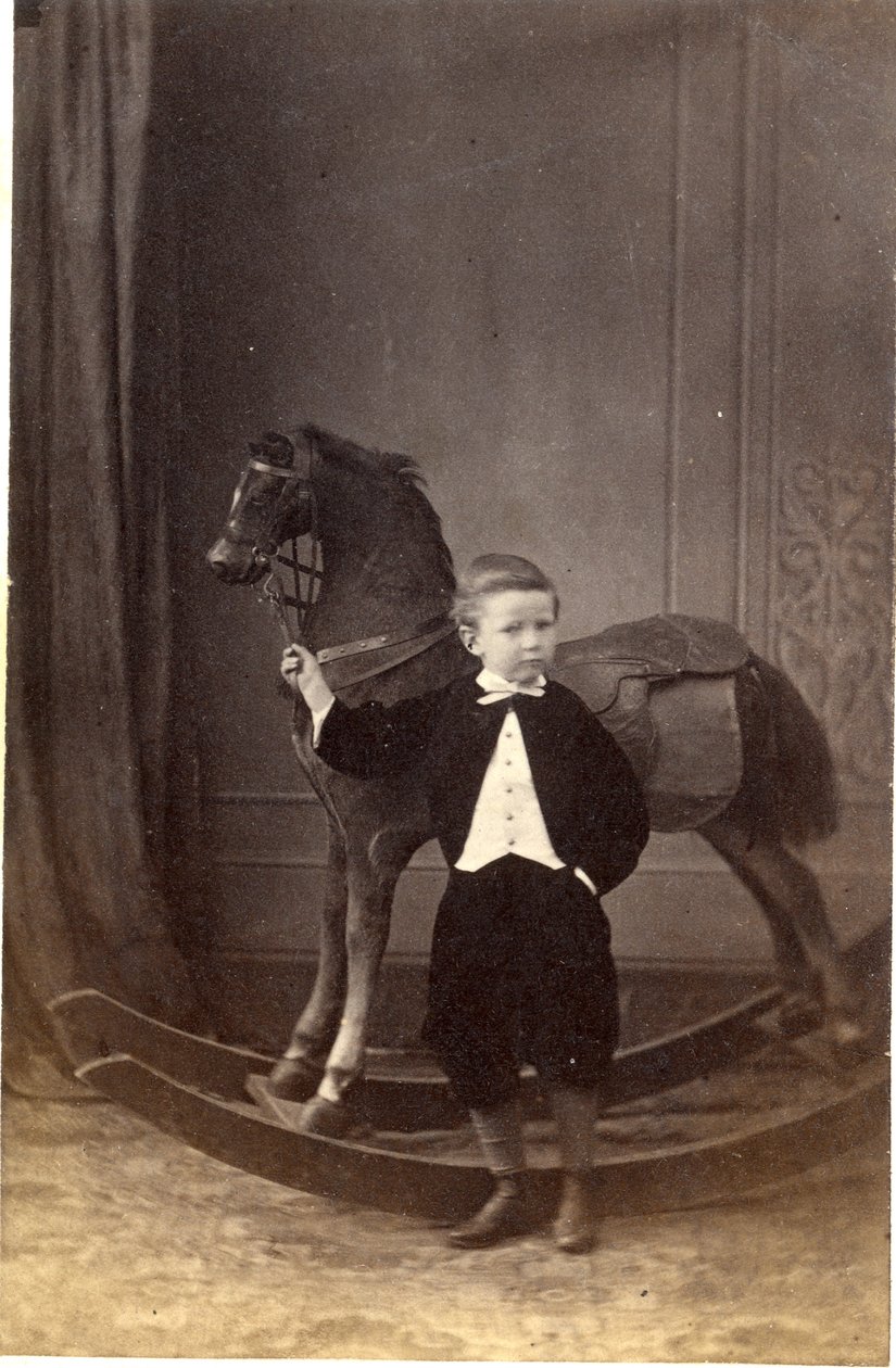 Boy Standing Holding Reins of a Rocking Horse by Barat
