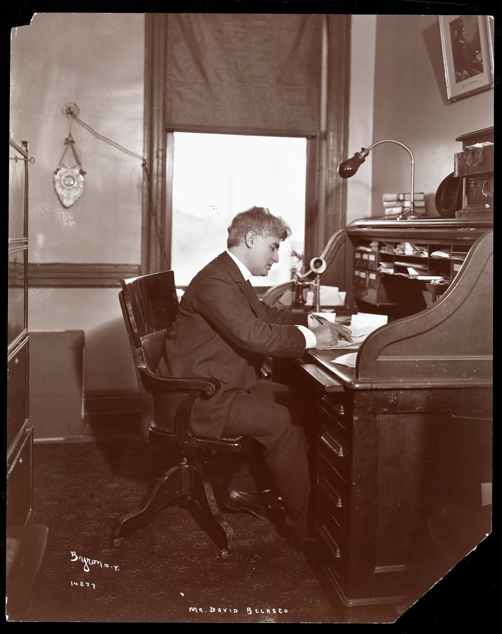 David Belasco writing at a desk in the offices of his theatre, 1902 by Byron Company