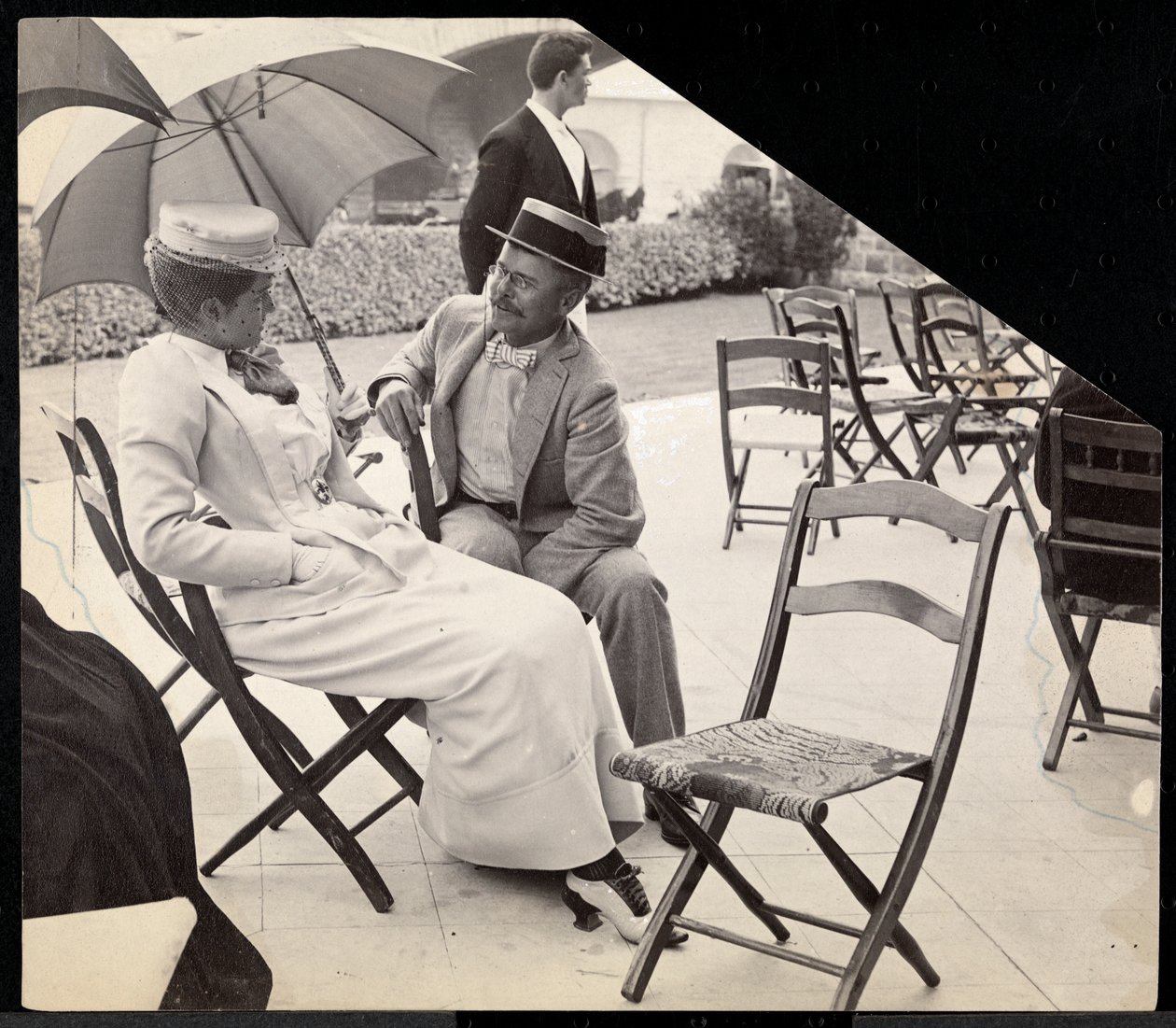 Man and woman seated outside on folding chairs with woman holding a parasol, Narragansett, Rhode Island, 1891 by Byron Company