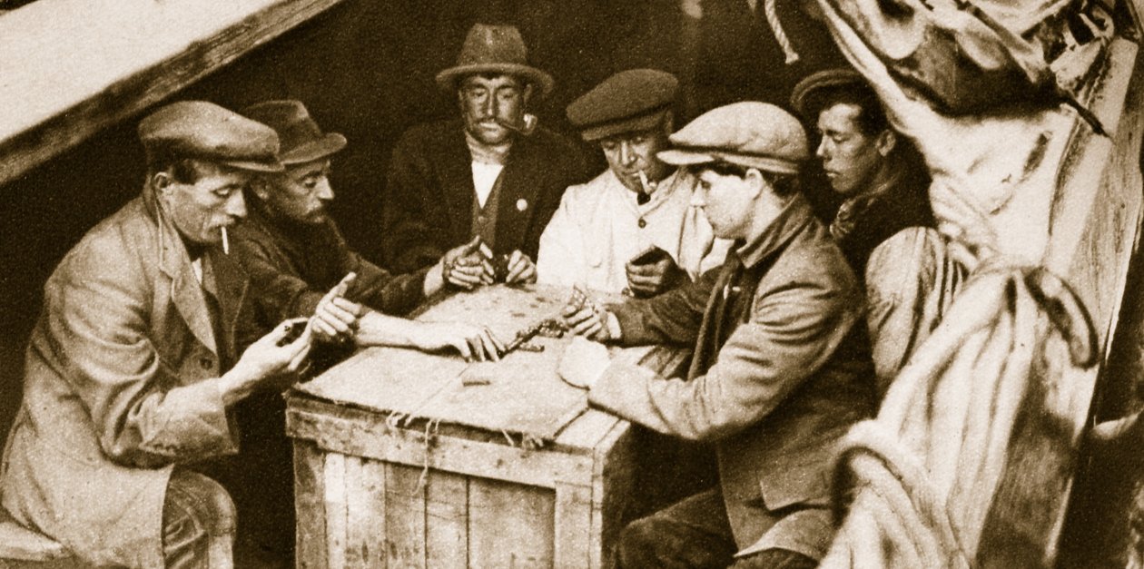 A bargee and friends playing dominoes in the hold of a barge, London by English Photographer