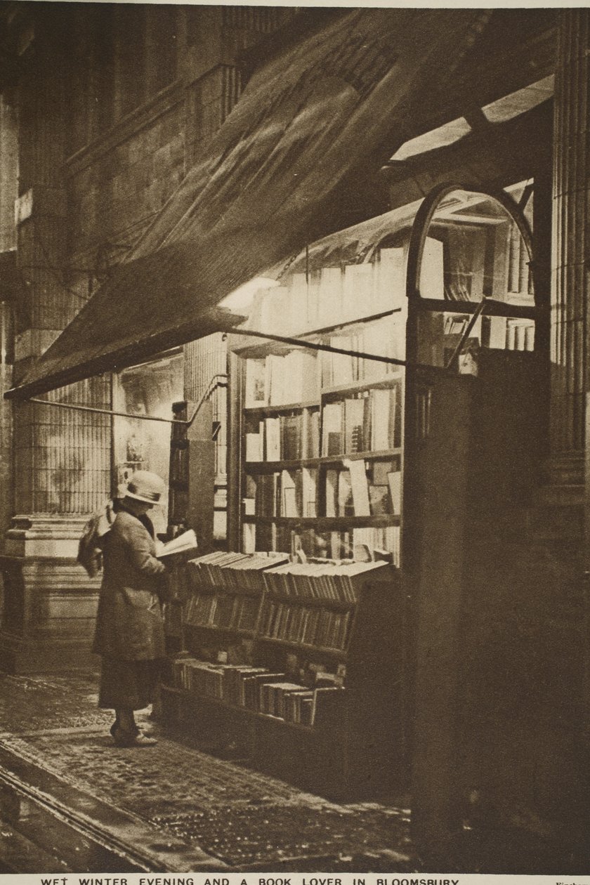 Examining a book outside a second hand bookshop on a wet winter evening, Bloomsbury by English Photographer