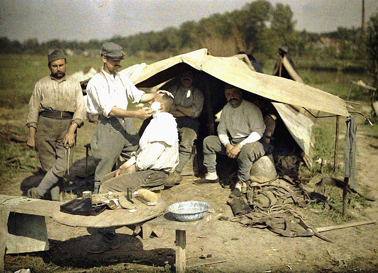 Soldier being shaved by a barber in a French military encampment, Soissons, Aisne, France by Fernand Cuville