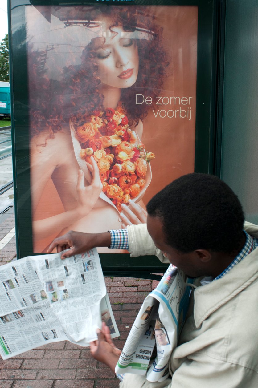 Man reading a newspaper in Brussels tram train stop in Brussels, Belgium by Unbekannt Unbekannt